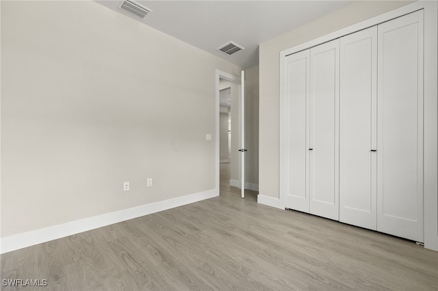 unfurnished bedroom with a closet and light hardwood / wood-style floors