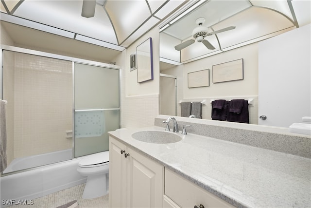 full bathroom featuring ceiling fan, toilet, combined bath / shower with glass door, and vanity