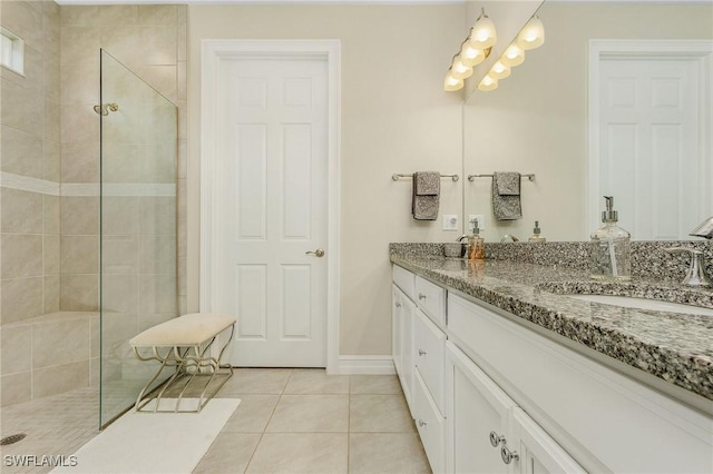 full bathroom featuring double vanity, a sink, a walk in shower, tile patterned flooring, and baseboards