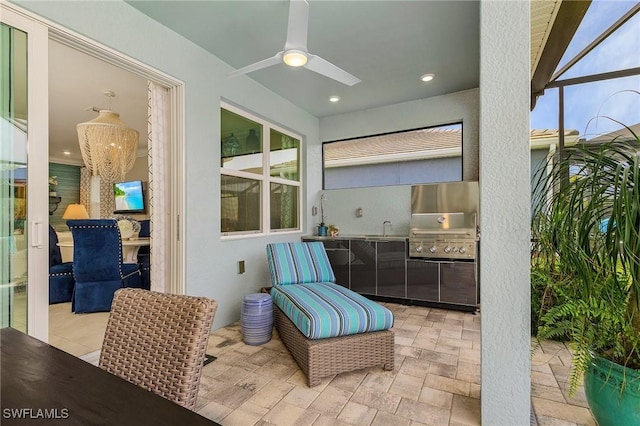 view of patio with a lanai, area for grilling, a sink, a ceiling fan, and exterior kitchen