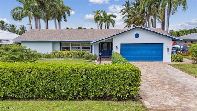 ranch-style home featuring stucco siding, decorative driveway, and an attached garage