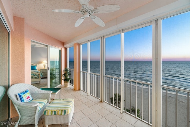 sunroom / solarium featuring a beach view, a water view, and ceiling fan