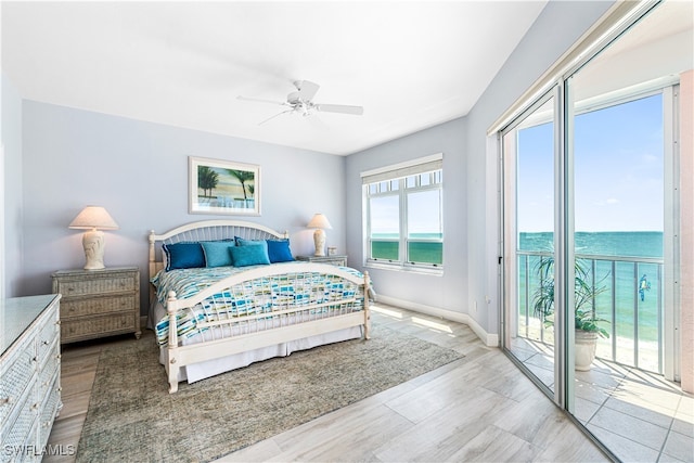 bedroom with light wood-type flooring, access to outside, ceiling fan, and a water view