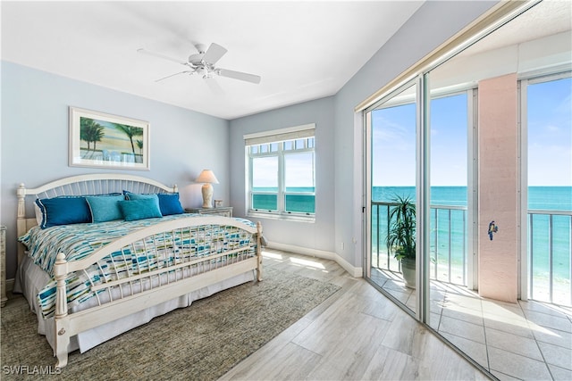 bedroom with light hardwood / wood-style floors, ceiling fan, a water view, and access to outside