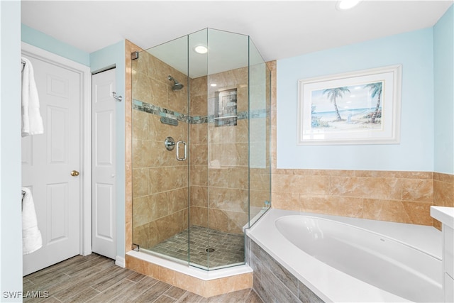 bathroom featuring wood-type flooring and separate shower and tub