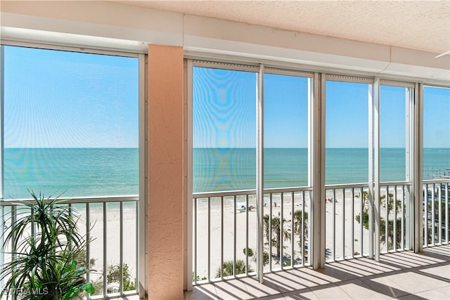 unfurnished sunroom with a view of the beach and a water view