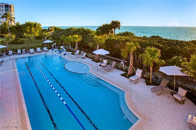 view of swimming pool featuring a water view and a patio