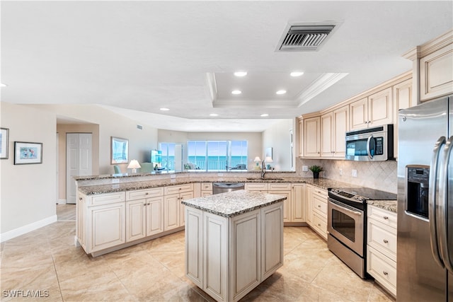 kitchen featuring cream cabinetry, a center island, stainless steel appliances, and kitchen peninsula