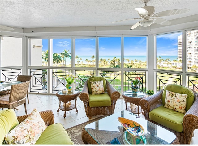 sunroom with ceiling fan, a water view, and a healthy amount of sunlight