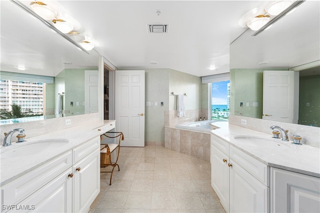 bathroom with vanity, tiled bath, and tile patterned flooring