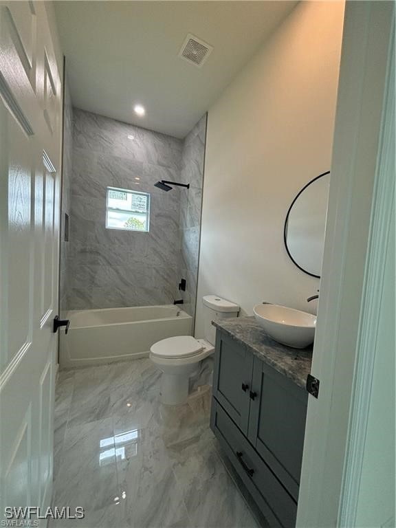 full bathroom featuring tiled shower / bath, vanity, and toilet