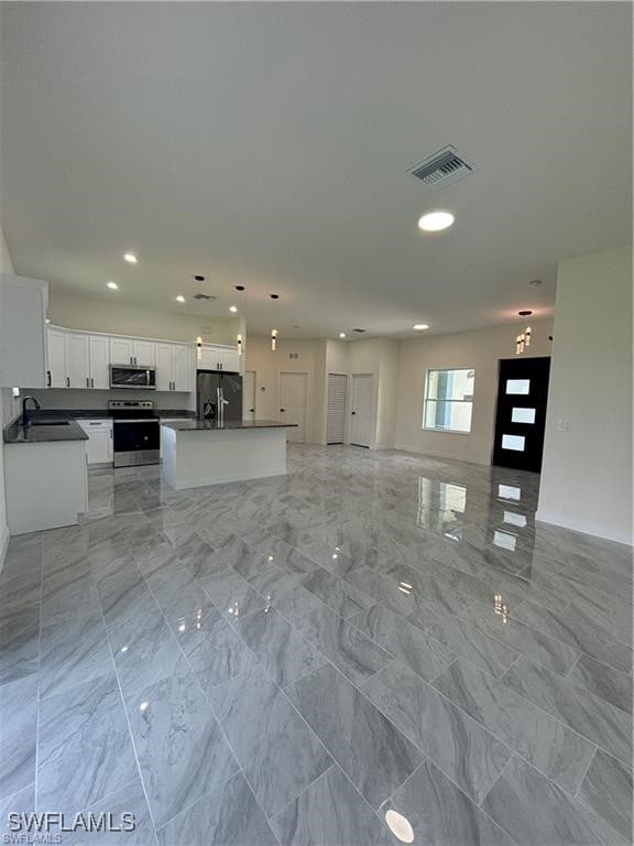 kitchen with sink, decorative light fixtures, a center island with sink, white cabinetry, and appliances with stainless steel finishes