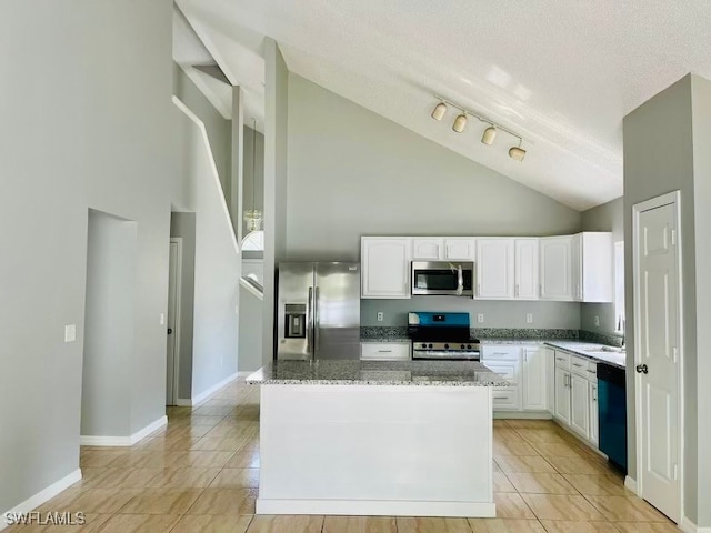 kitchen with white cabinets, stone counters, appliances with stainless steel finishes, a kitchen island, and a textured ceiling