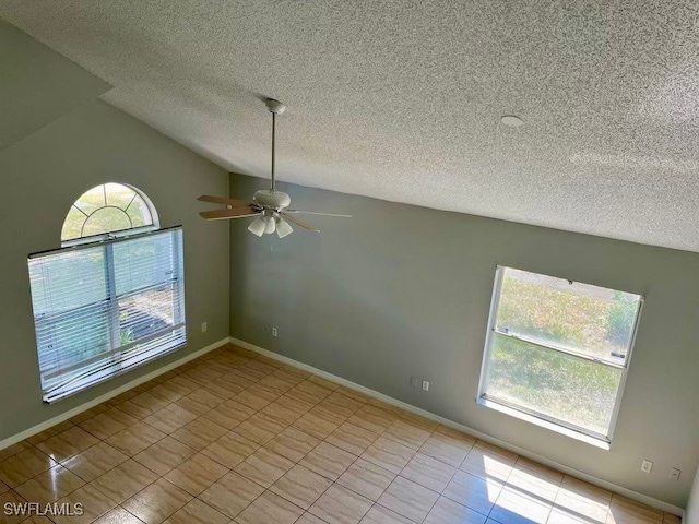 empty room with lofted ceiling, light tile patterned floors, ceiling fan, and a textured ceiling