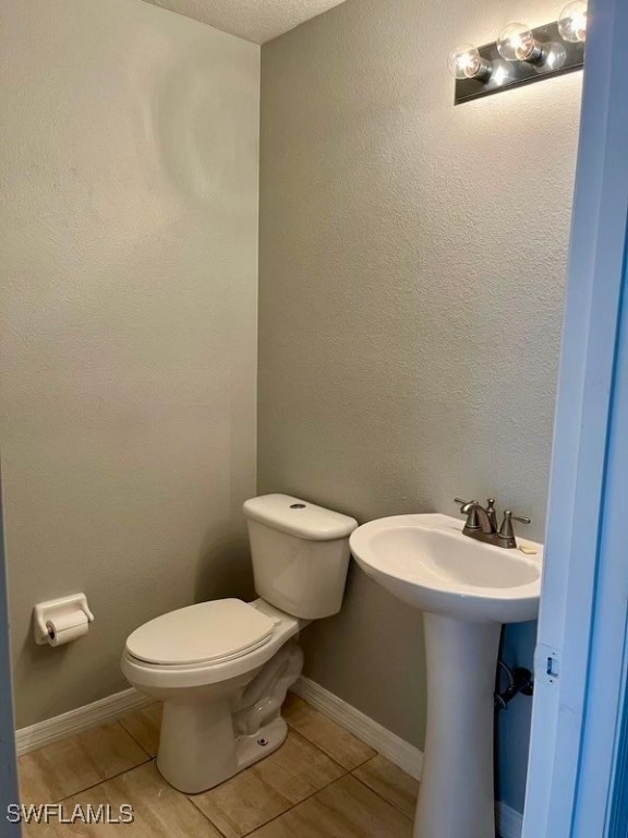 bathroom featuring a textured ceiling, toilet, and tile patterned floors