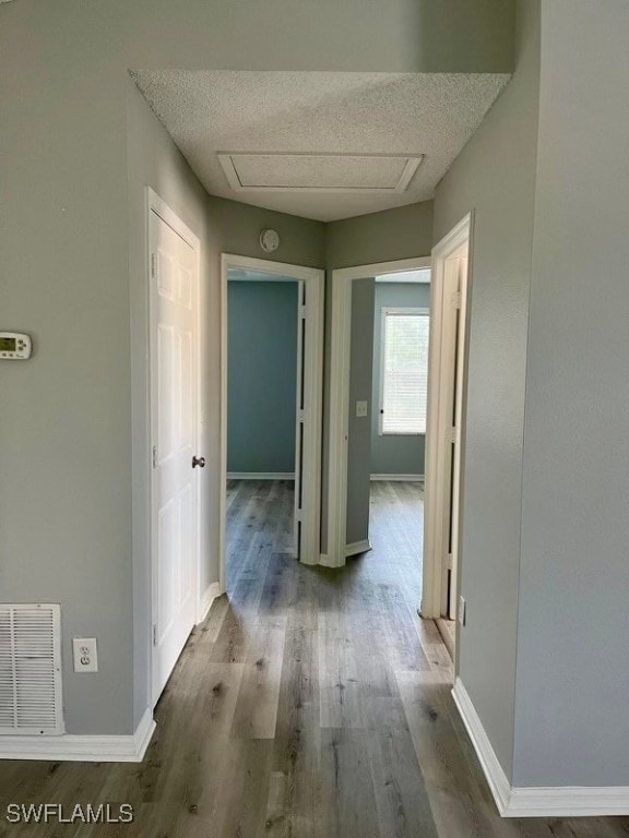 corridor with a textured ceiling and hardwood / wood-style flooring