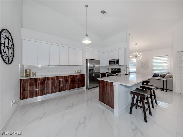 kitchen with hanging light fixtures, stainless steel appliances, a chandelier, and white cabinetry