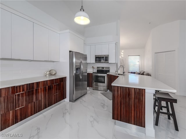 kitchen with pendant lighting, a breakfast bar, stainless steel appliances, sink, and kitchen peninsula