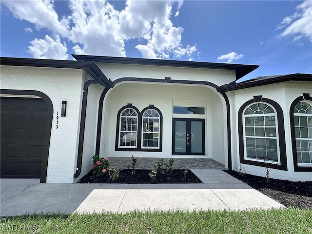 view of exterior entry featuring french doors and a garage