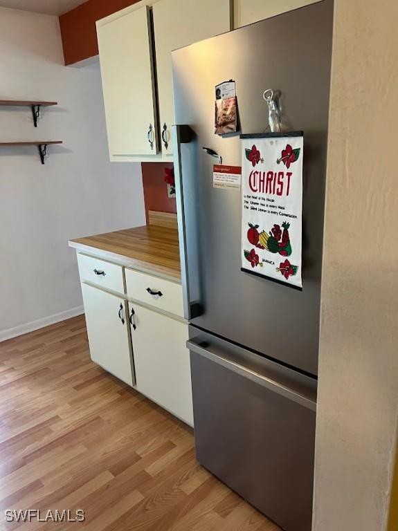 52 Heath Aster Ln, Lehigh Acres, FL 33936 - kitchen with freestanding refrigerator, light wood-style flooring, white cabinets, light countertops, and open shelves
