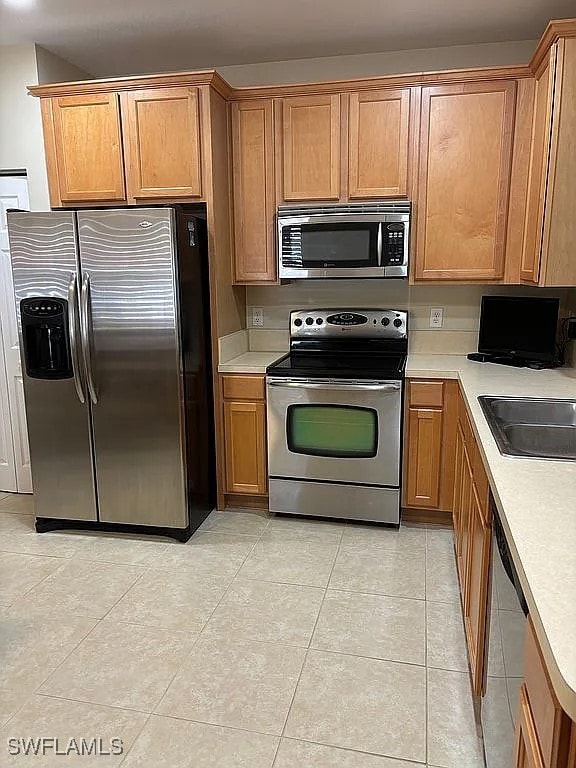 kitchen with sink, stainless steel appliances, and light tile patterned flooring