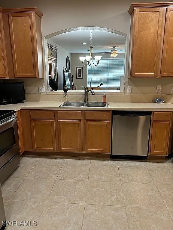 kitchen featuring appliances with stainless steel finishes, light tile patterned flooring, sink, ceiling fan with notable chandelier, and decorative light fixtures