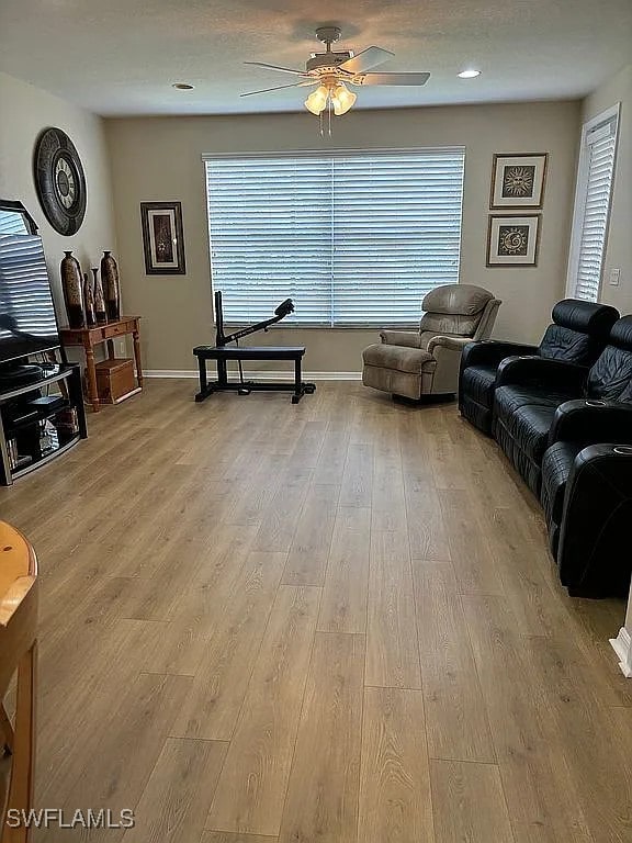 living room featuring light hardwood / wood-style floors, ceiling fan, and a wealth of natural light