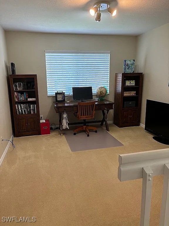 carpeted home office featuring a textured ceiling