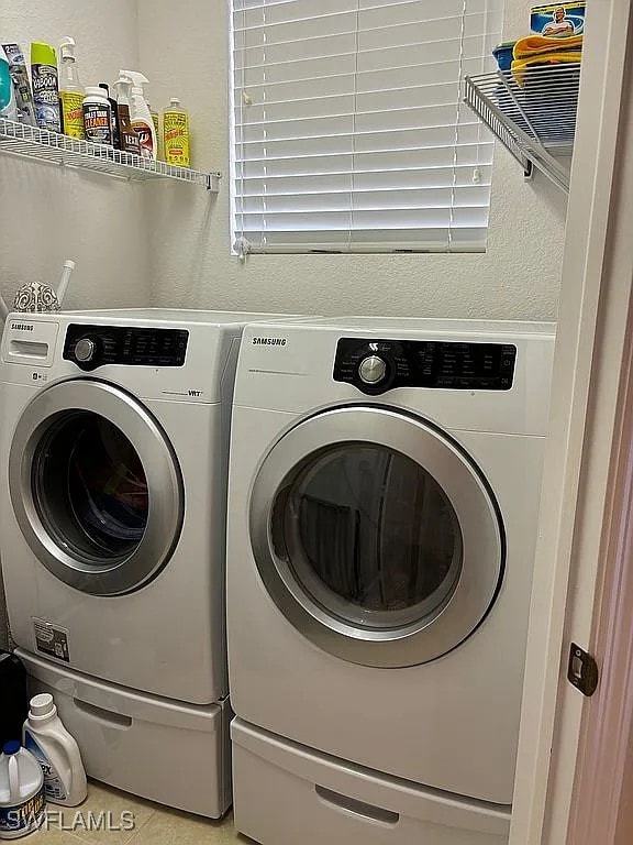 clothes washing area with independent washer and dryer and light tile patterned floors