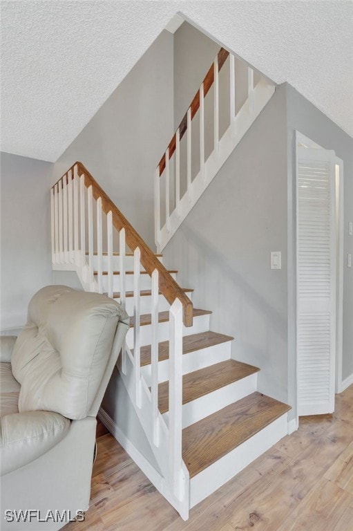 stairs with hardwood / wood-style flooring and a textured ceiling