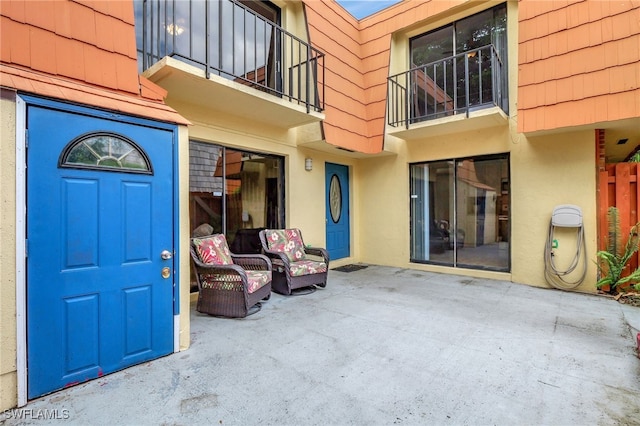 doorway to property with stucco siding, a patio, and a balcony