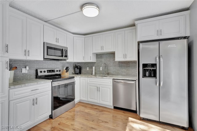 kitchen featuring stainless steel appliances, light hardwood / wood-style floors, white cabinetry, and sink