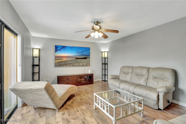 living room with a textured ceiling, light hardwood / wood-style flooring, and ceiling fan