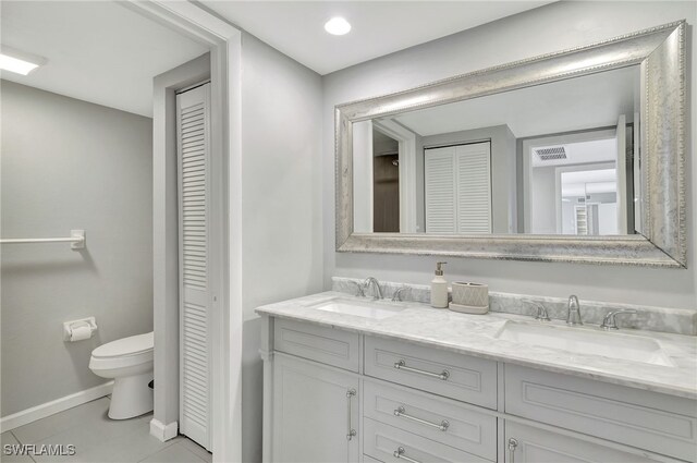 bathroom with double vanity, a closet, toilet, and a sink
