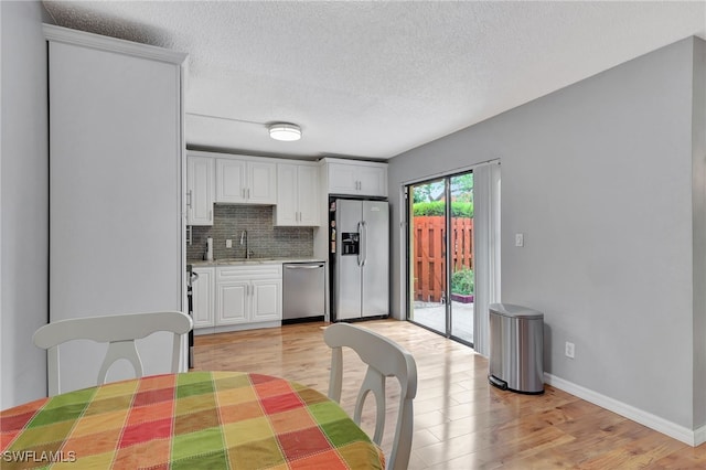 kitchen with white cabinetry, light hardwood / wood-style flooring, stainless steel appliances, and sink