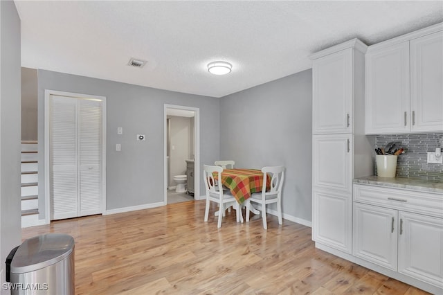 dining area with a textured ceiling and light hardwood / wood-style flooring