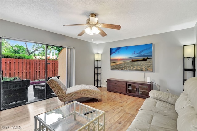 living room with a textured ceiling, light hardwood / wood-style flooring, and ceiling fan