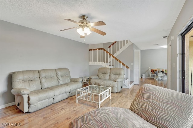 living room featuring ceiling fan, a textured ceiling, and light hardwood / wood-style flooring