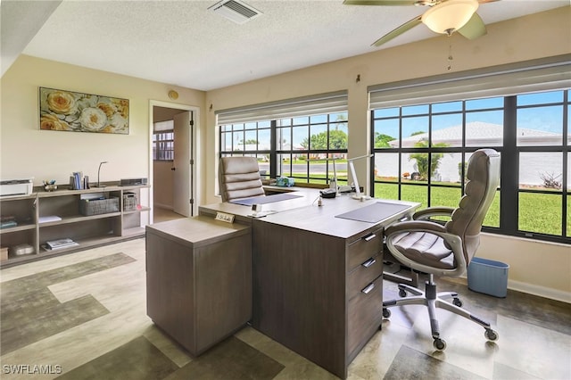 office space featuring ceiling fan, a textured ceiling, and a healthy amount of sunlight