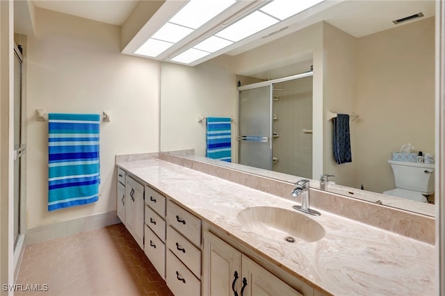 bathroom with an enclosed shower, vanity, toilet, and tile patterned floors