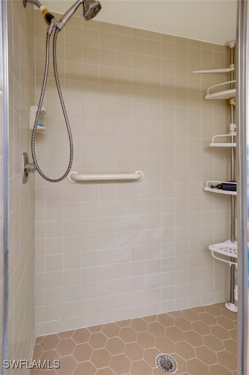 bathroom with tiled shower and tile patterned flooring