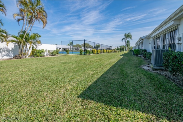 view of yard featuring central AC unit and tennis court