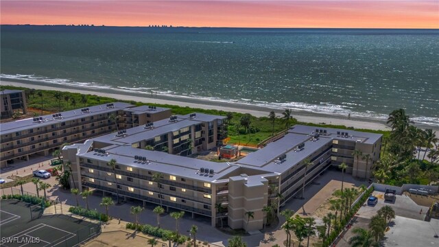 aerial view at dusk with a view of the beach and a water view