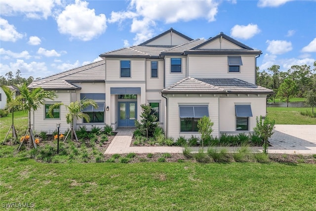 view of front facade featuring a front lawn, french doors, and a tile roof