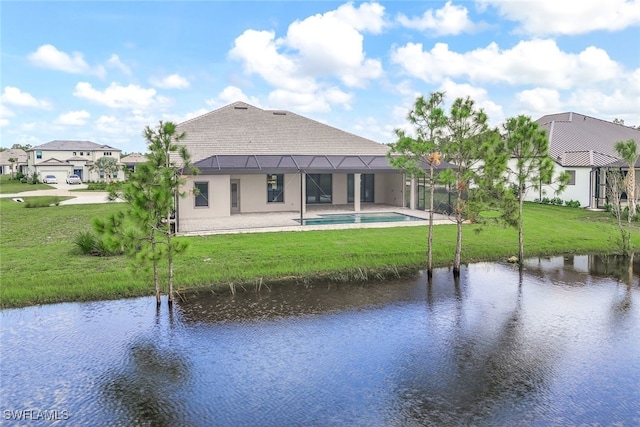 rear view of house featuring a lanai, a water view, and a lawn