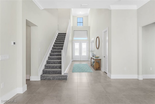 staircase with a high ceiling, crown molding, and a healthy amount of sunlight