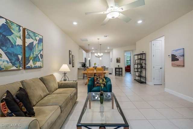 tiled living room with ceiling fan with notable chandelier