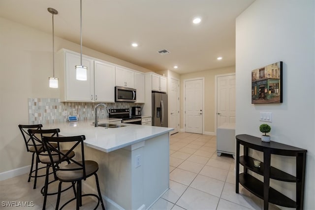 kitchen featuring white cabinets, hanging light fixtures, stainless steel appliances, sink, and kitchen peninsula