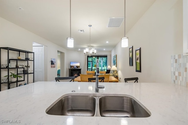 kitchen with decorative light fixtures, light stone counters, and a chandelier