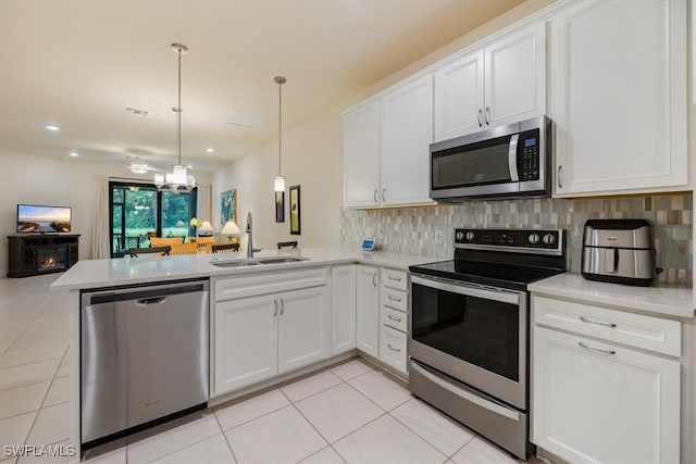 kitchen featuring kitchen peninsula, sink, appliances with stainless steel finishes, and white cabinetry